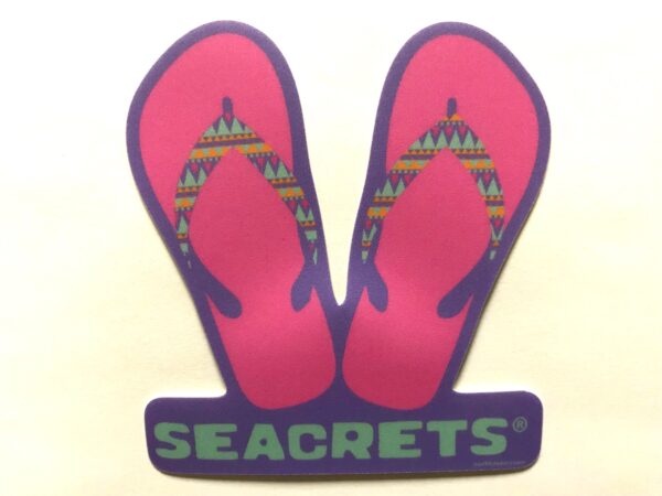 a pair of pink flip flops sitting on top of a sign